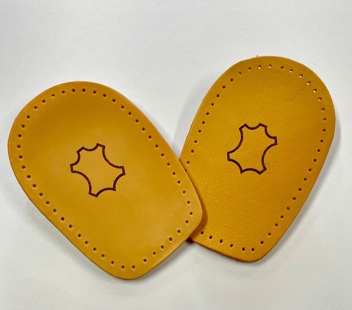 Two tan leather insole templates with pre-drilled holes and a leather stamp outline in the center, displayed on a white background.